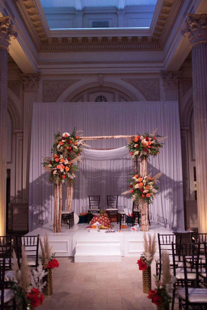 Large wooden arch with drapery and orange flowers