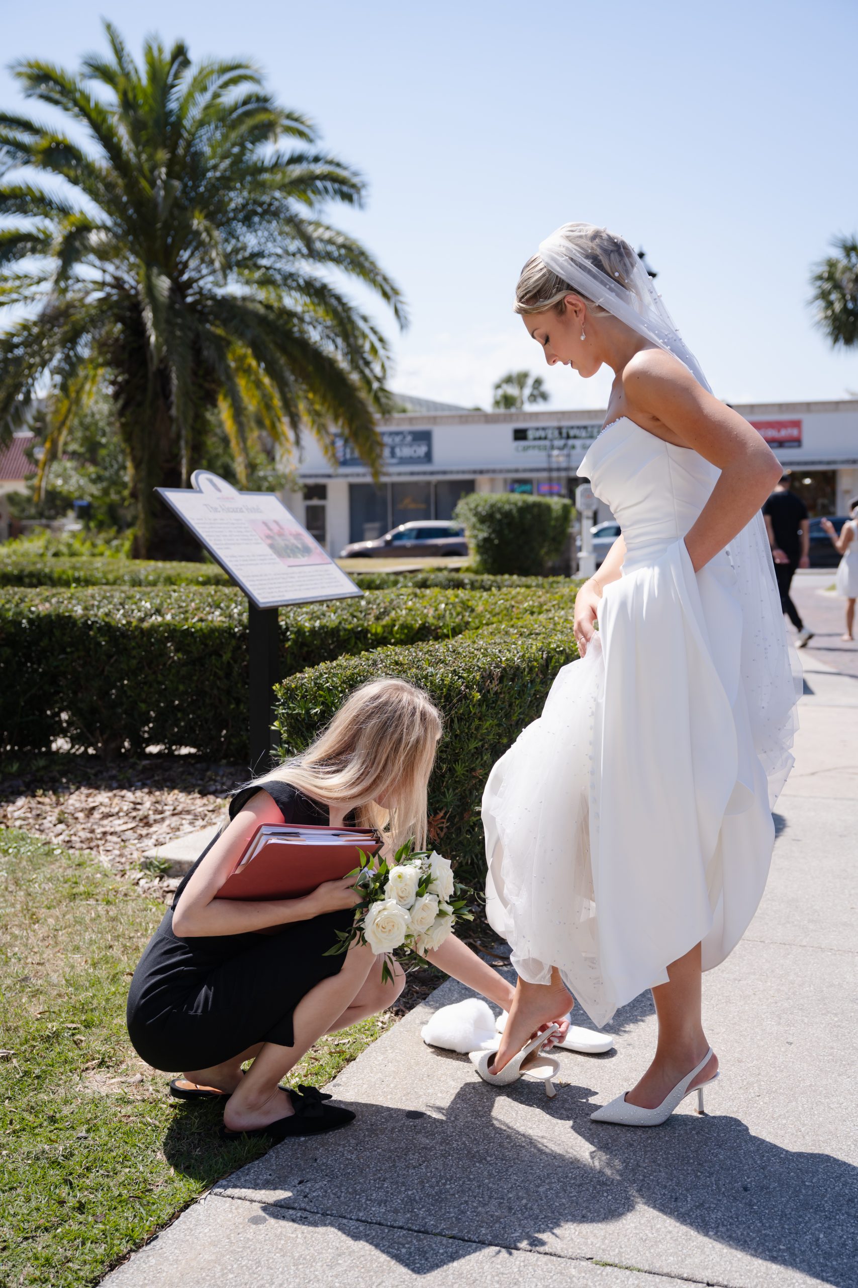 bride getting dress adjustments by wedding coordinator