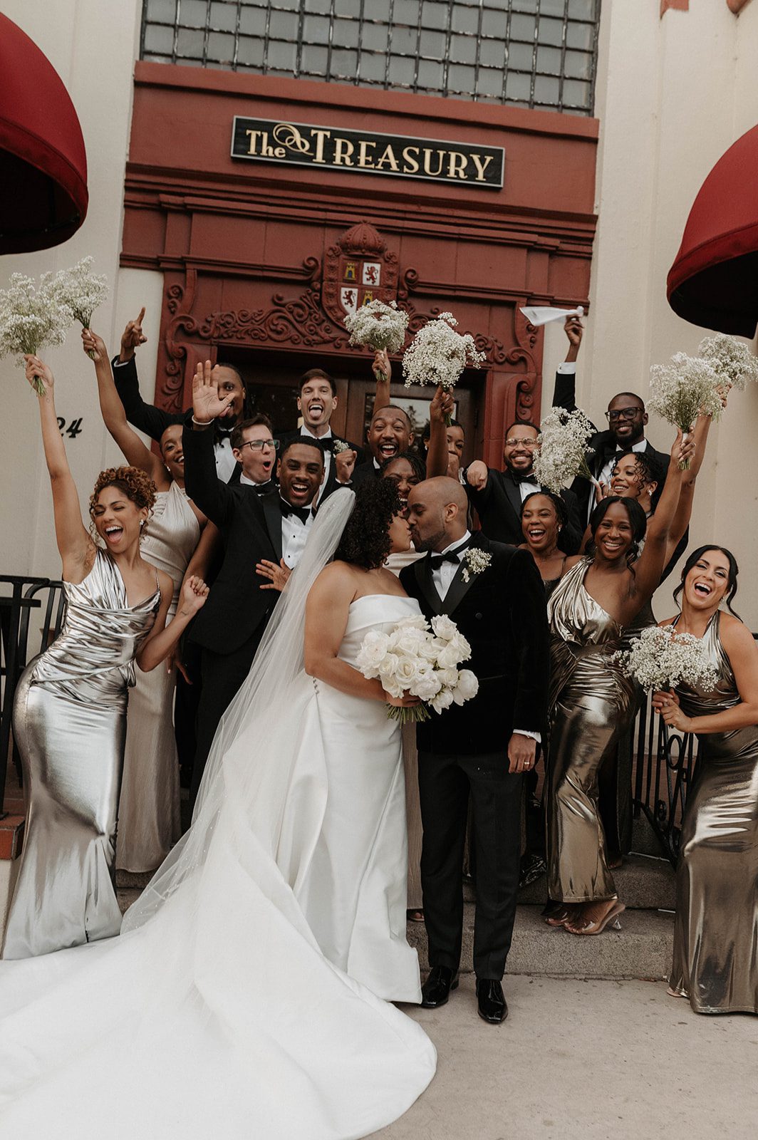 Ariel and James share a kiss with their wedding party in front of The Treasury on the Plaza. | Photo: Spencer Luca Photo