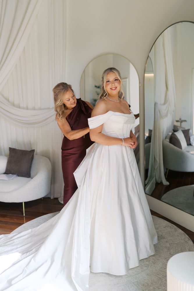 Mother helping daughter into her wedding dress