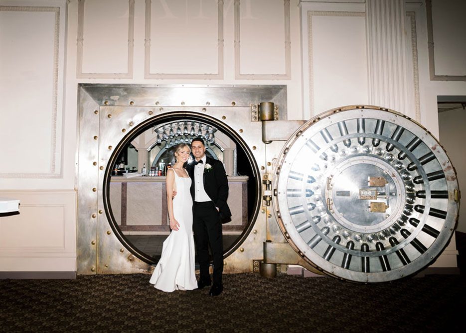 Bride and groom posing in front of the original vault door at The Treasury