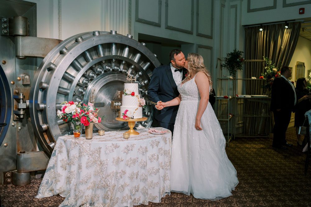 Bride and groom cutting their wedding cake beside the Vault Bar